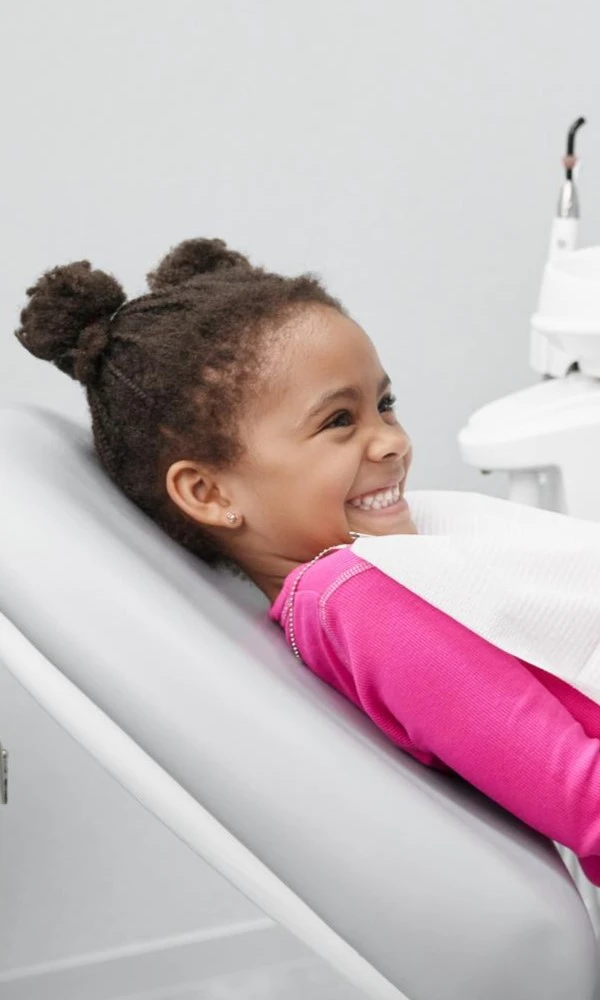 Afro Girl In Pink Top Smiling In Dental Chair
